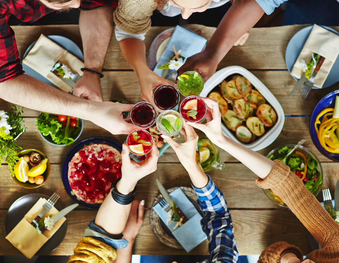 People cheers at table with drinks in hand and small plates on the table in restaurant
