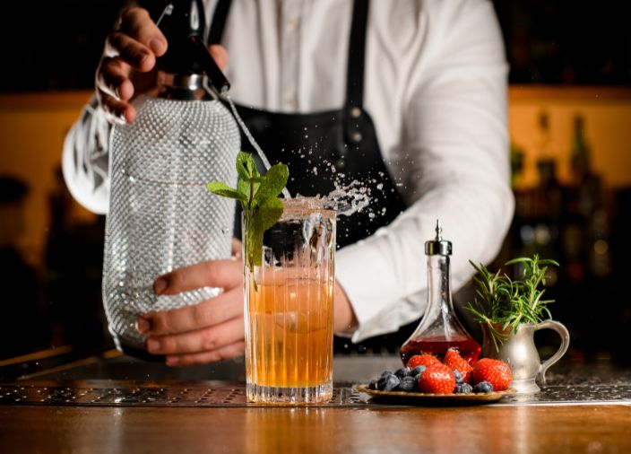 bartender adding splash of soda water to cocktail