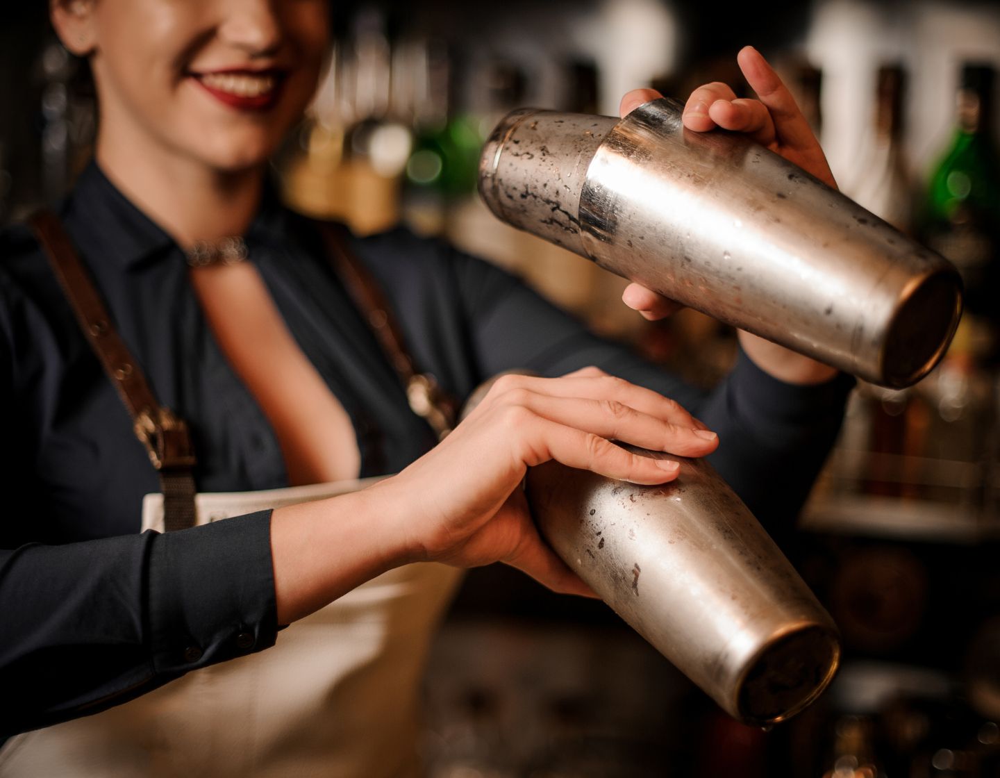 Bartender detrás de la barra con dos cocteleras