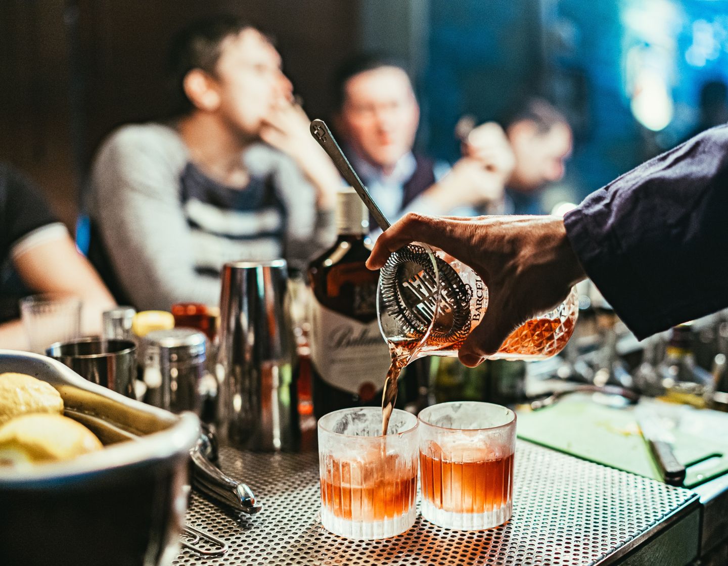 Two cocktails being strained from a shaker into glasses