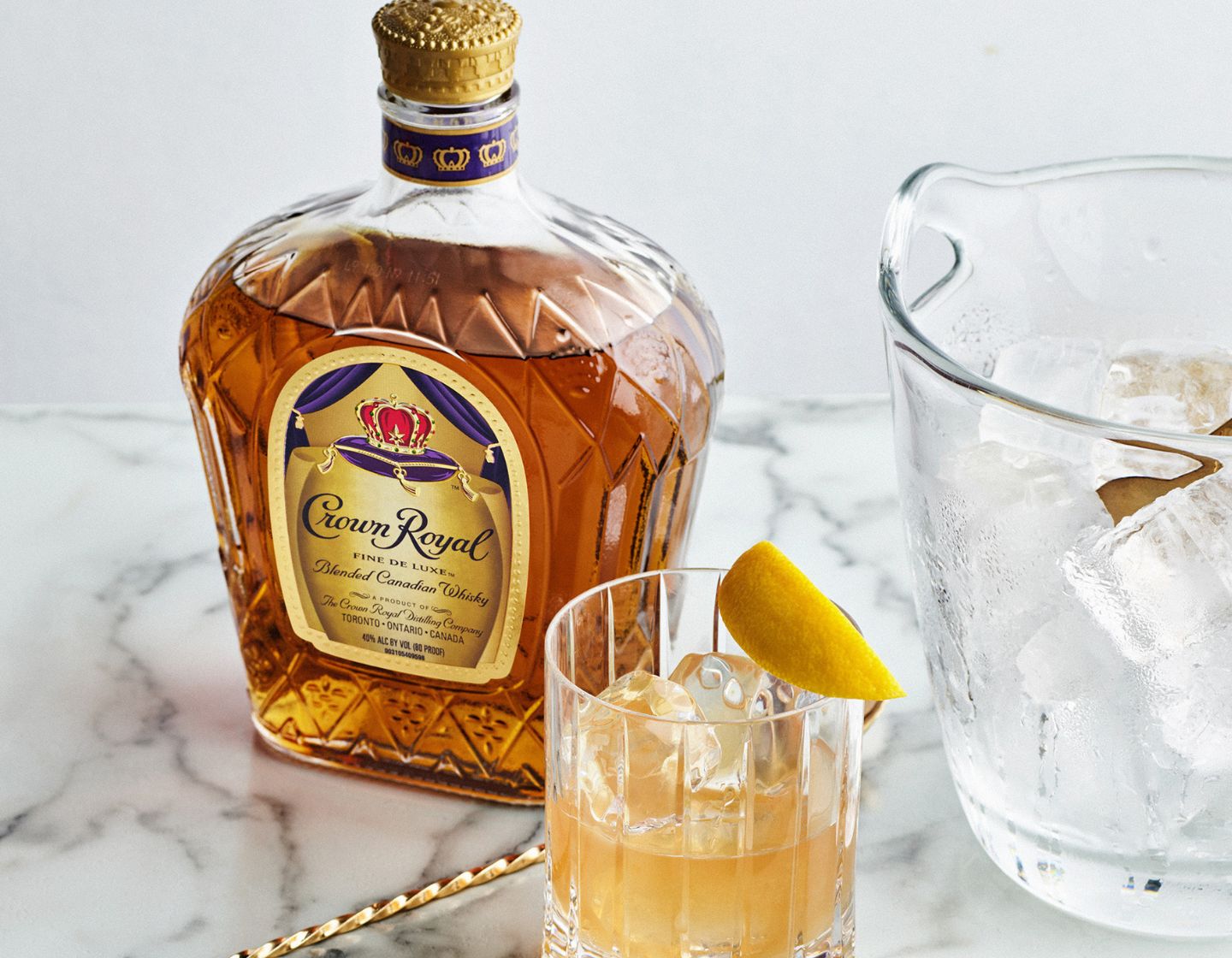Eine Flasche Crown Royal Whisky auf einem Tisch neben einem Cocktail in einem Coupe Glas