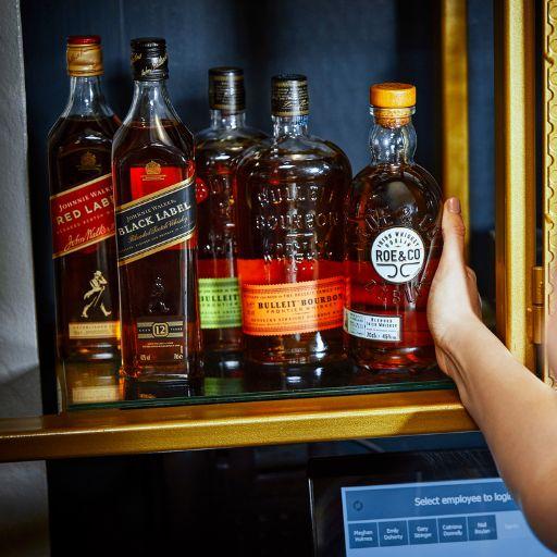 bartender lifting roe and co from range of whiskies