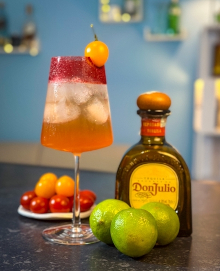 Cocktail steht neben einer Flasche und Früchten