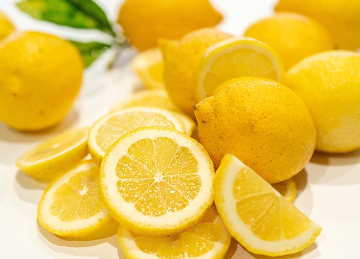 Limones enteros y en rodajas sobre un fondo blanco.