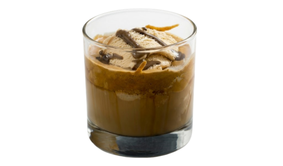 Sobremesa affogato em copo de vidro baixo e transparente. Uma bola de sorvete claro flutua sobre café com espuma, decorada com calda de chocolate escura no topo. Fundo branco isolado.
