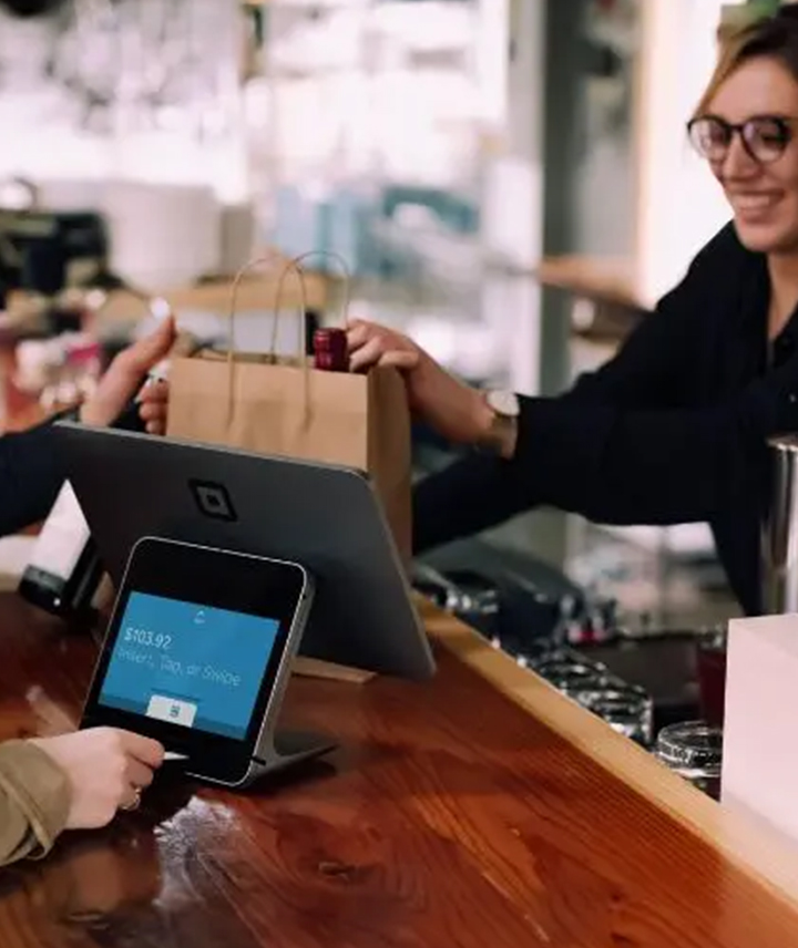 A man and woman pay for items at a bar using a screen POS terminal.