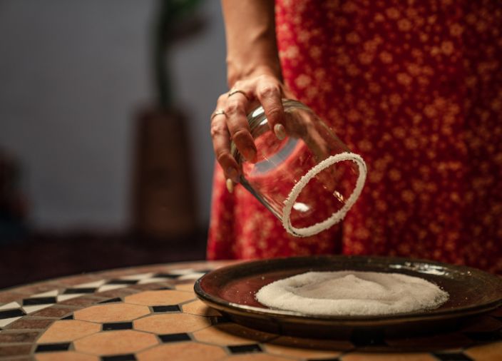 Las manos de una persona sosteniendo un vaso de Margarita sobre un platillo de sal.