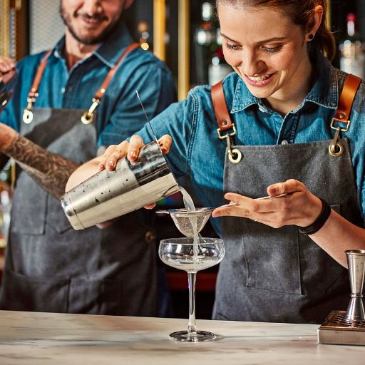 Bartenders working together, pouring from shaker into glass 