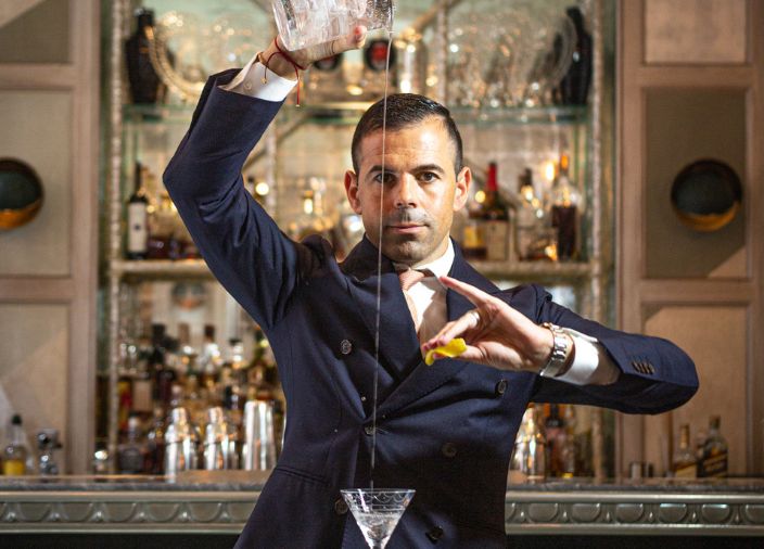 Imagen de Ago Perrone vertiendo un chorro fino de un líquido en una copa de martini.