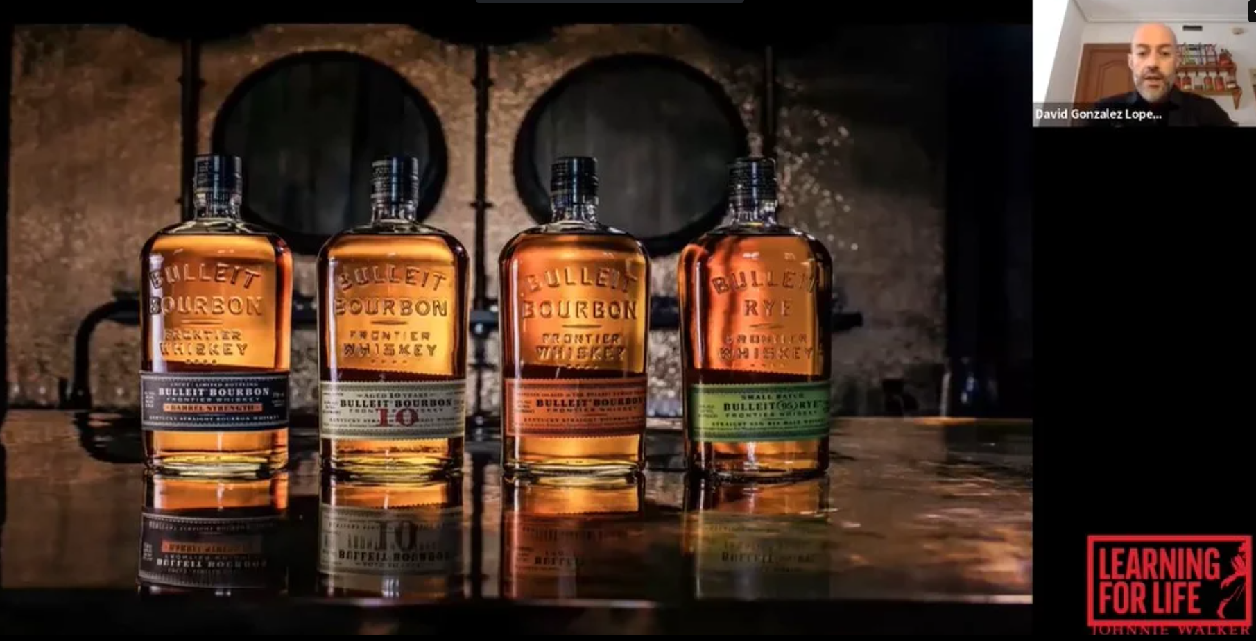 Hombre vertiendo un cóctel en un vaso sobre una mesa junto a una botella abierta de whisky Bulleit    