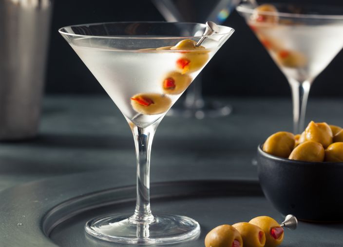 Martini de color claro en una copa de Martini con aceitunas.