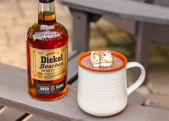An enamel mug of smores hot cholocate with a bottle of George Dickel 8 year old Bourbon