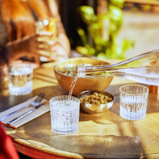Bebida servida en un vaso transparente con comida y pequeños platos en la mesa 
