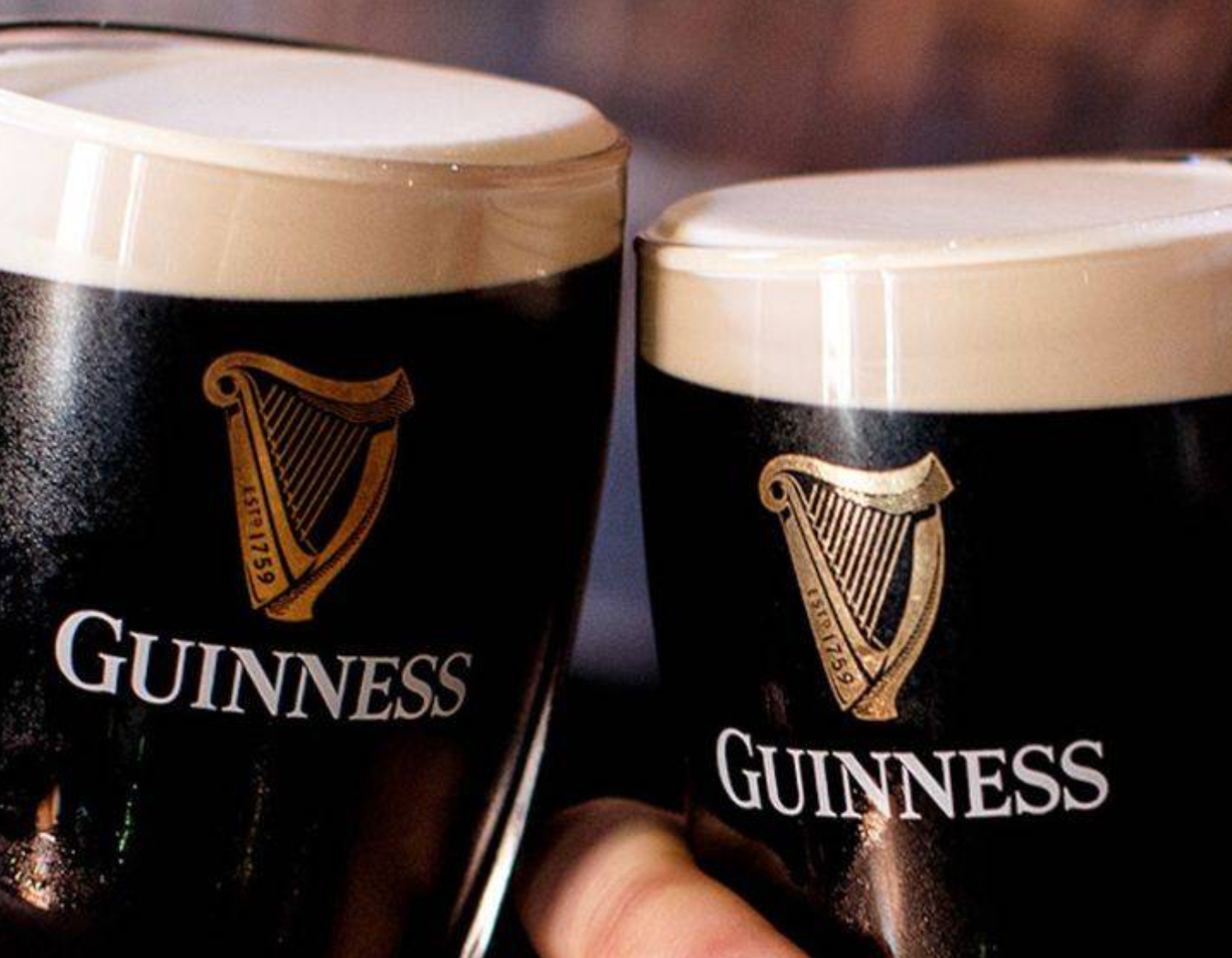 Two pints of Guinness tapping together for a cheers. 