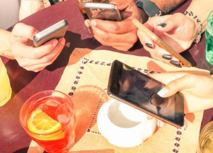 People with phones out at a table of drinks