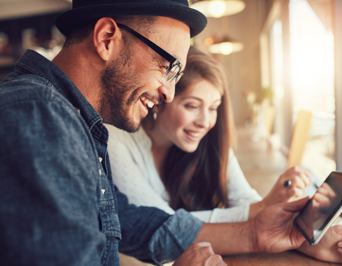 Man and Woman in bar looking and smiling at mobile phone to engage in social media
