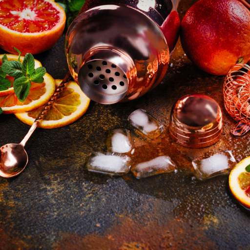 Fruits and shaker lying on the table, spilled cocktail