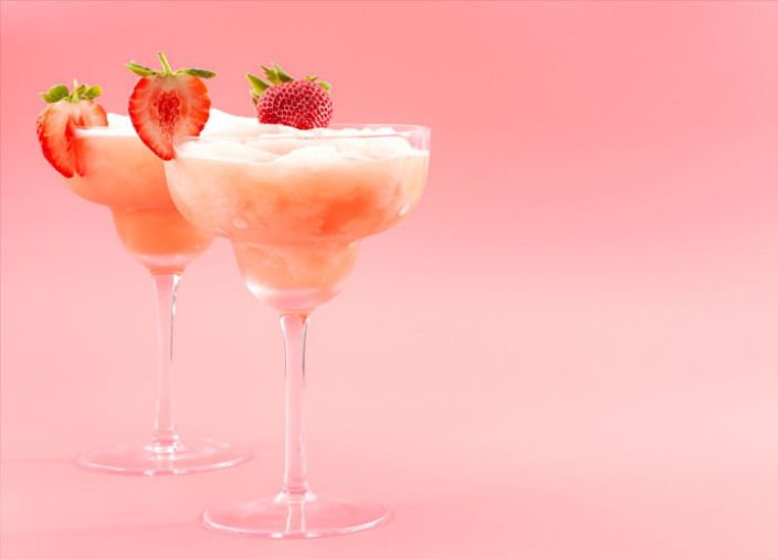 Two pink liquid drinks with layers and strawberry