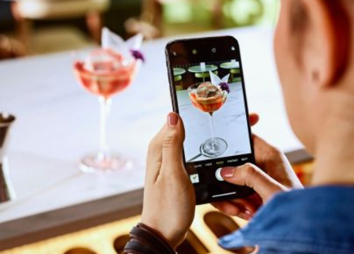 Woman taking picture of cocktail with phone