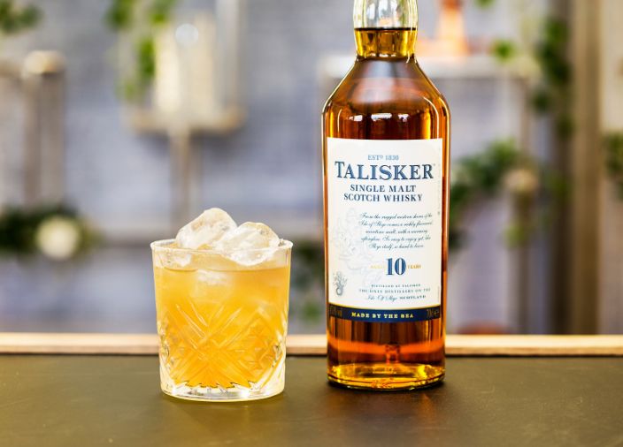 Whisky bottle accompanied by a yellow whisky cocktail with ice