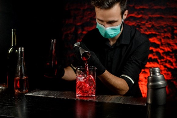 Imagem de um bartender com luvas usando um dosador 