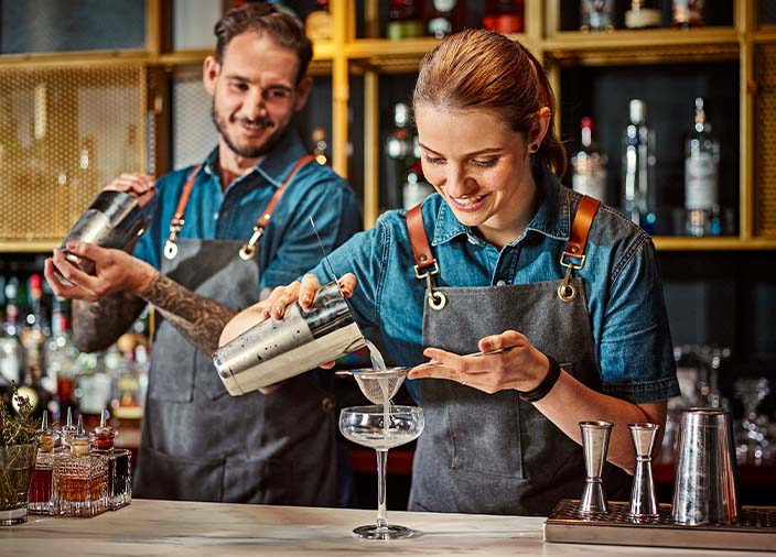 Two bartenders working together behind the bar  
