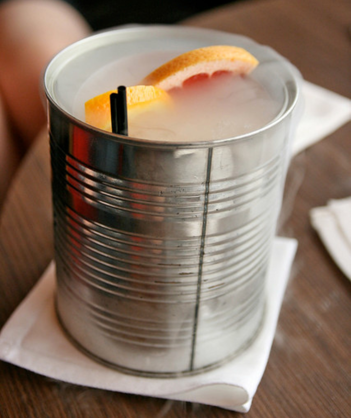 Cocktail, orange-infused vodka, mango, passion fruit and chilli served in a tin can with a rosemary and marjoram fog and orange garnish.