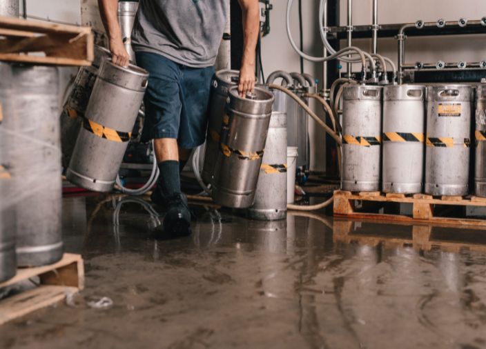 Barback moving kegs of beer in storeroom