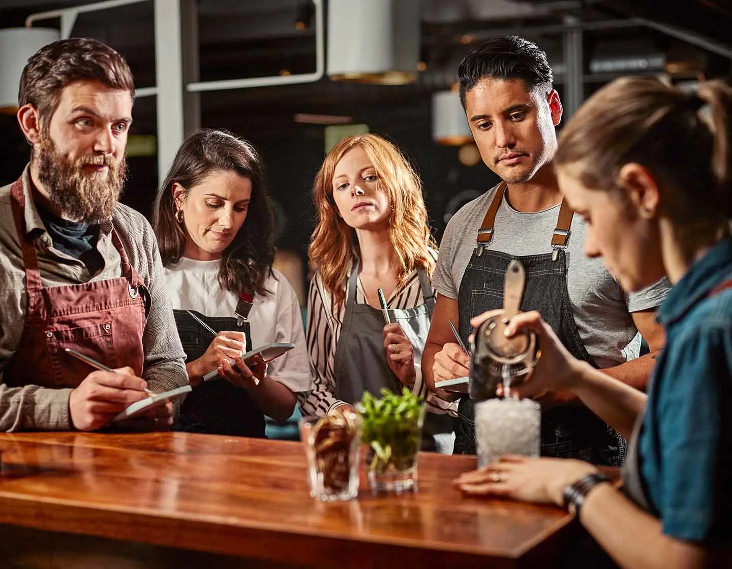 21st birthday party ideas with an instructor demonstrating cocktail making to students taking notes for a cocktail-making class
