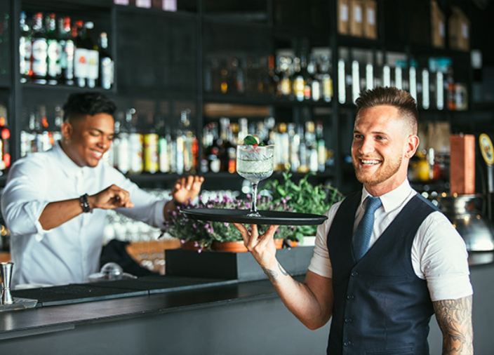 Imagem de um garçom e um bartender em serviço