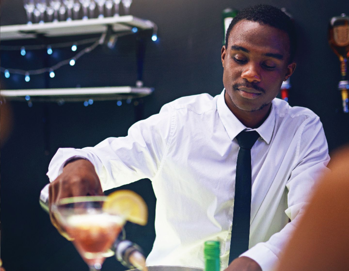 Bartender pouring a drink into a cocktail glass.