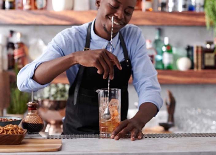 A bartender stirs a cocktail mix in a jug.