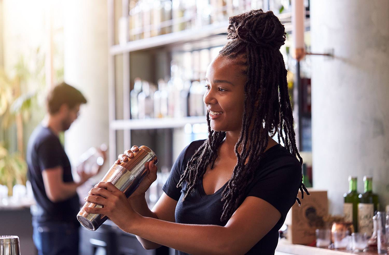 Bartender mulher agitando uma coqueteleira no bar