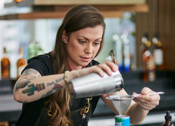 Mujer sirviendo una bebida utilizando herramientas de bar