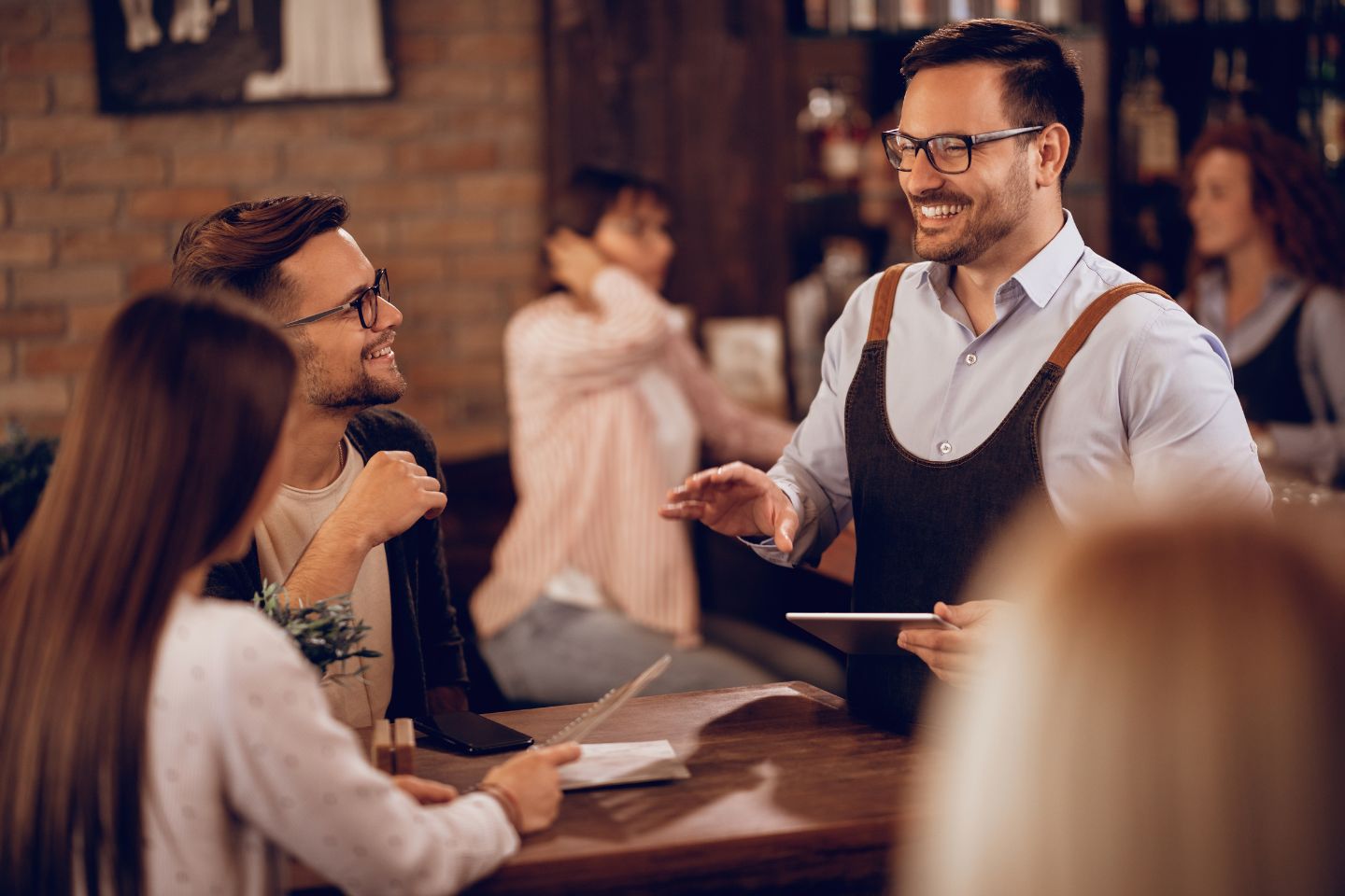 Bartender serving customers at a table.