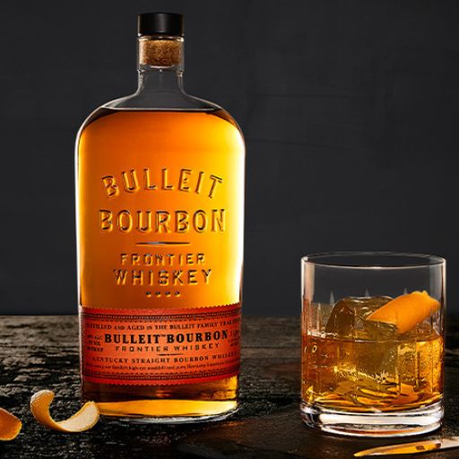 Bottle of Bulleit Bourbon next to a whiskey serve. 