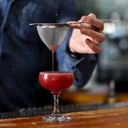 Pouring a cocktail through a fine filter