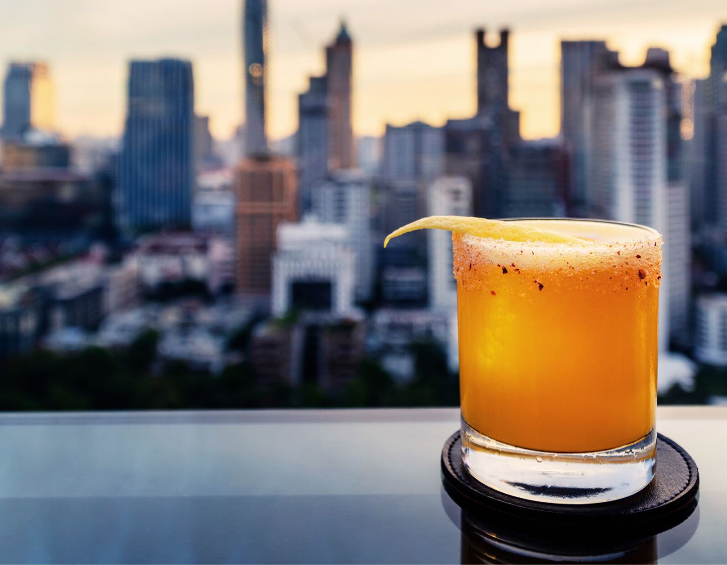 Orangener Cocktail vor Skyline