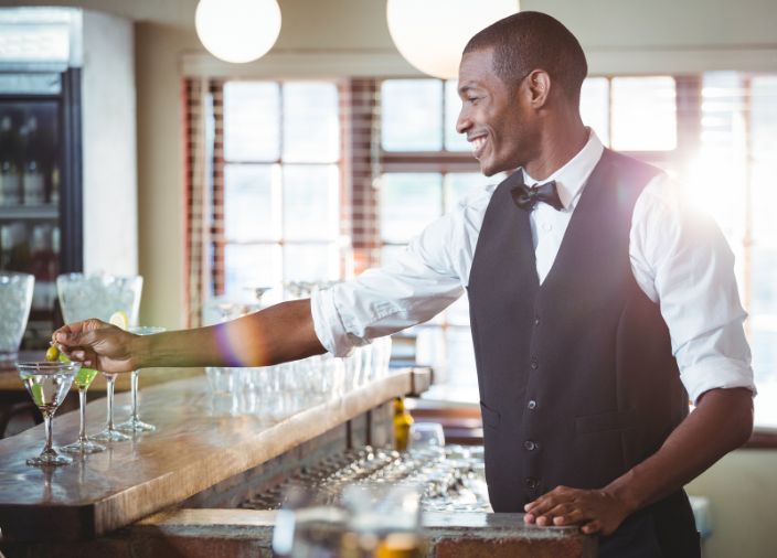 Imagem de um bartender conversando com um convidado enquanto prepara um coquetel