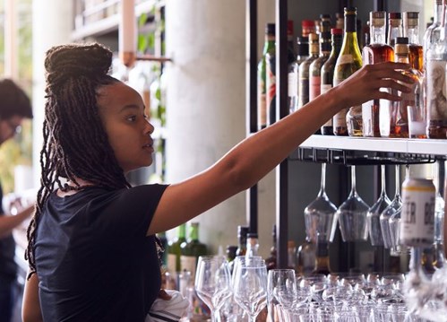 Una bartender agarrando una botella