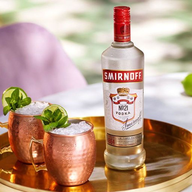 Smirnoff-Flasche neben zwei Cocktails in Bechern 