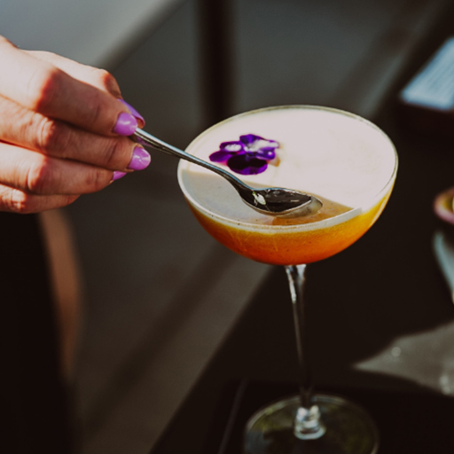 Hand using spoon to prepare cocktail