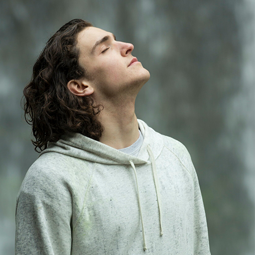 A man with his head tilted backwards, his eyes closed, looking serene wearing a light coloured hoodie.