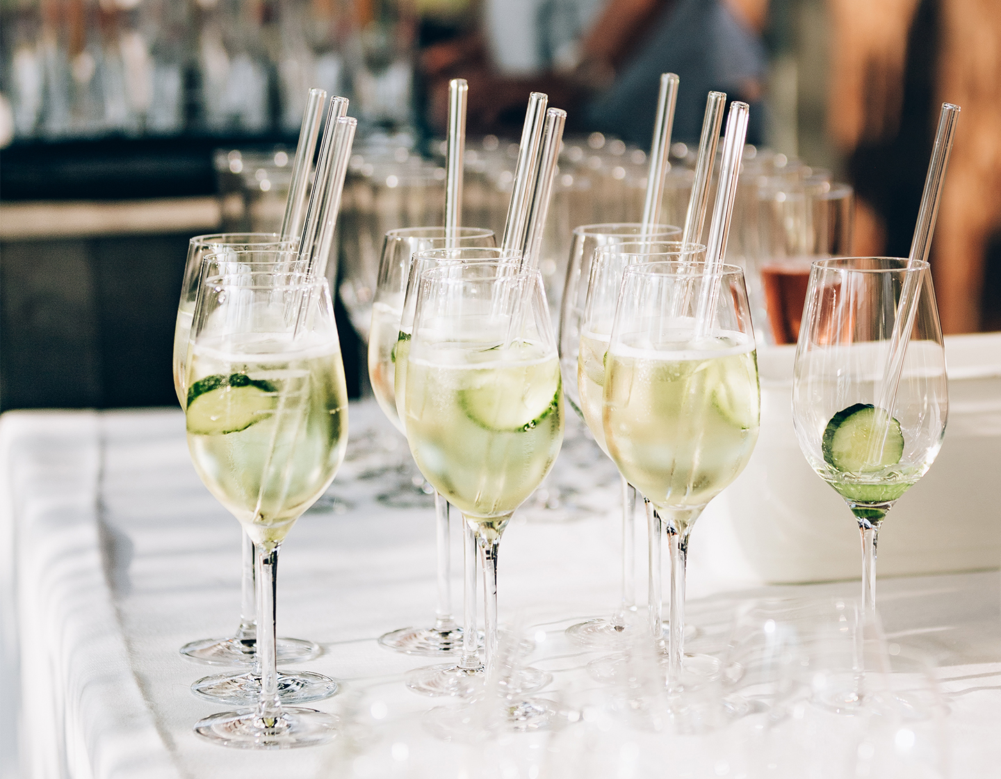 Un grupo de vasos de aperitivo idénticos con pajitas de cristal y hielo con una rodaja de pepino.