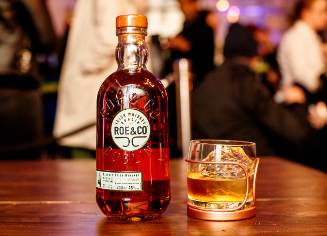Glass of whiskey drink with spices being added by hand from above
