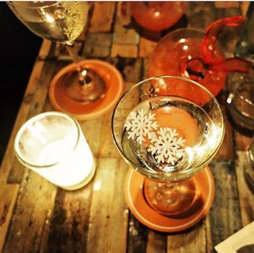 Ein Drink steht neben einer Kerze und anderen Gläsern auf einem Holztisch