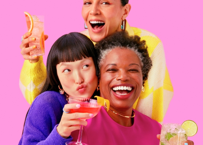 Colourful image of three women holding Smirnoff cocktails