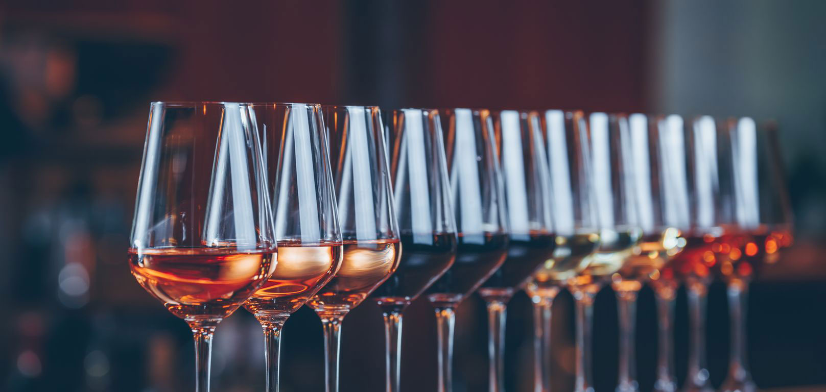 uma fileira de taças de vinhos de cores diferentes