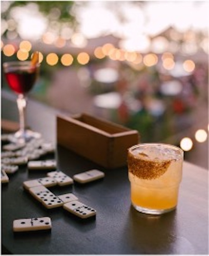 Ein Glas Tequile neben Dominosteinen auf einem Tisch