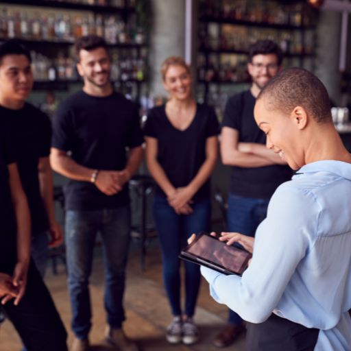  A bar manager talking to her team with a smile